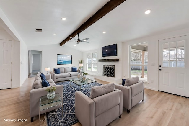 living room featuring vaulted ceiling with beams, light hardwood / wood-style flooring, and a healthy amount of sunlight