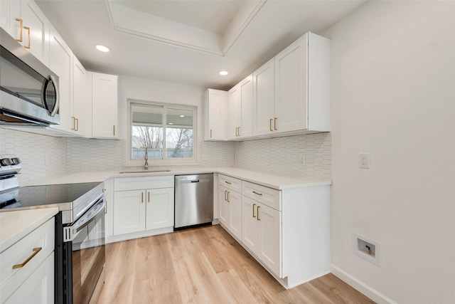 kitchen featuring white cabinetry, backsplash, light wood-type flooring, and appliances with stainless steel finishes