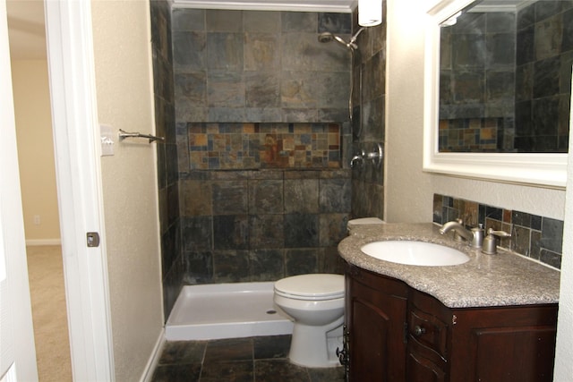 bathroom featuring a tile shower, vanity, and toilet