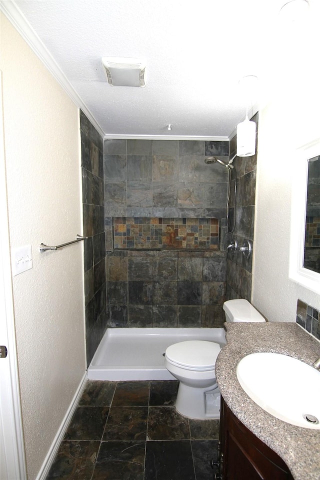 bathroom featuring tiled shower, ornamental molding, toilet, and vanity