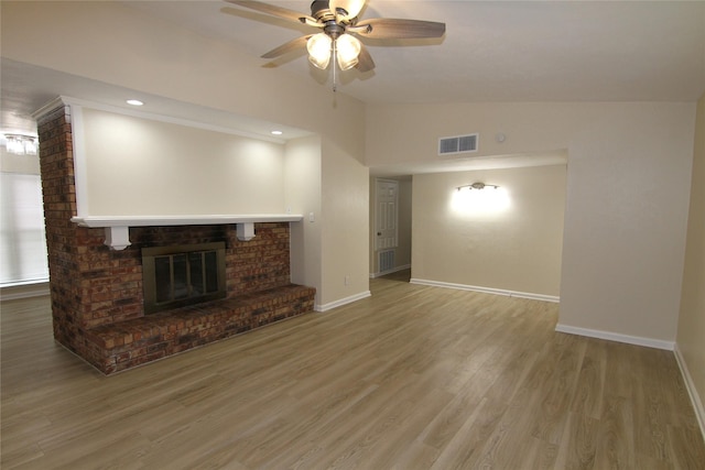 unfurnished living room with ceiling fan, lofted ceiling, wood-type flooring, and a brick fireplace