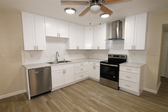 kitchen with wall chimney exhaust hood, sink, white cabinetry, stainless steel appliances, and light hardwood / wood-style floors