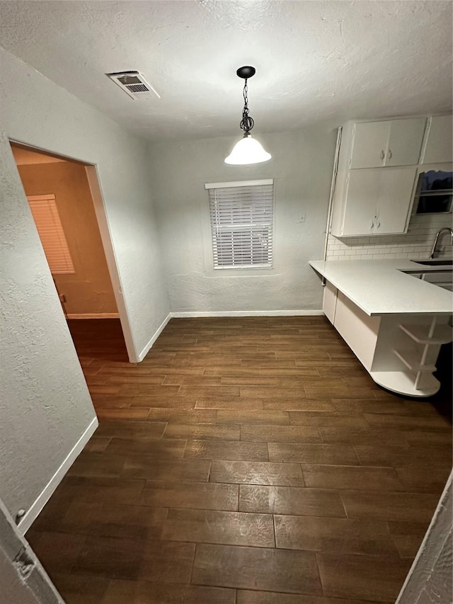 unfurnished dining area featuring dark hardwood / wood-style flooring, sink, and a textured ceiling