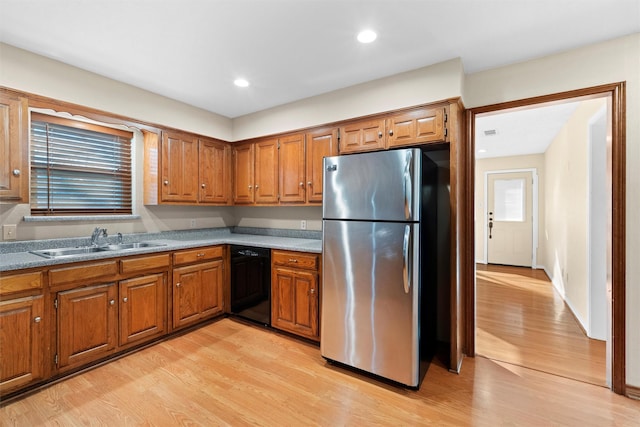 kitchen featuring dishwasher, sink, stainless steel refrigerator, and light hardwood / wood-style floors