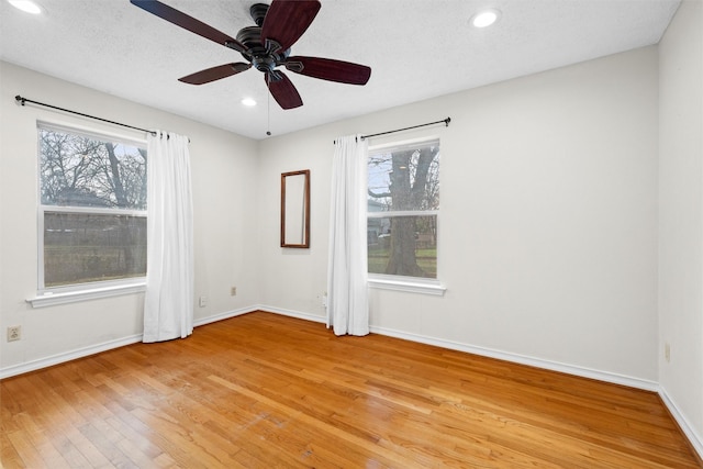 unfurnished room featuring ceiling fan, a wealth of natural light, a textured ceiling, and light hardwood / wood-style flooring