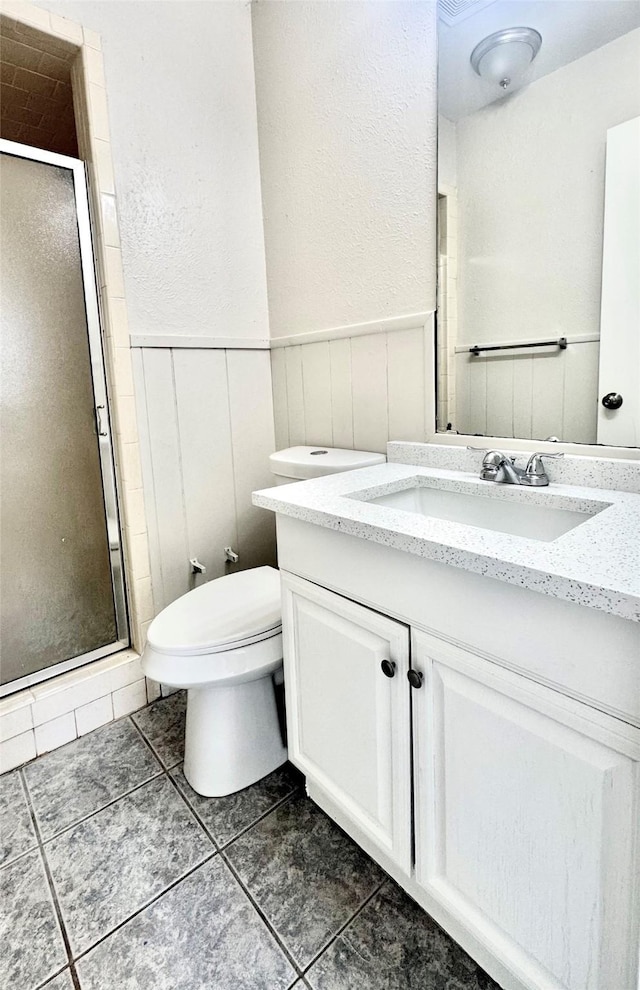 bathroom featuring tile patterned floors, vanity, toilet, and a shower with door