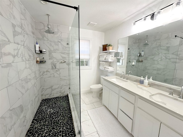 bathroom featuring marble finish floor, tiled shower, a sink, and toilet