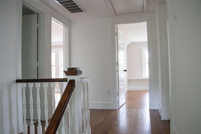 hall featuring baseboards, visible vents, an upstairs landing, and wood finished floors