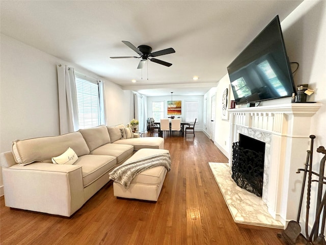 living room featuring ceiling fan, a fireplace, and wood finished floors