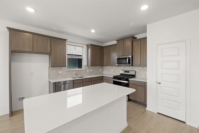 kitchen featuring tasteful backsplash, stainless steel appliances, dark brown cabinets, light countertops, and a sink