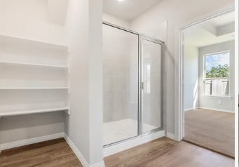 bathroom featuring a stall shower, wood finished floors, and baseboards