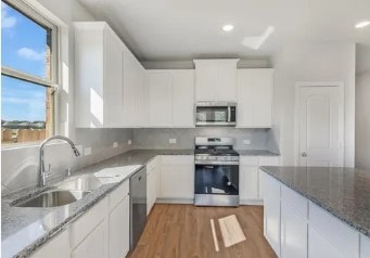 kitchen featuring light stone counters, appliances with stainless steel finishes, and white cabinets