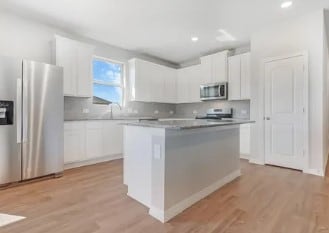 kitchen featuring a kitchen island, white cabinetry, appliances with stainless steel finishes, and light wood-type flooring