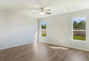 unfurnished room with ceiling fan, baseboards, and wood finished floors