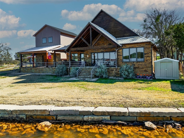 view of front of home featuring a porch, a storage unit, and a front lawn