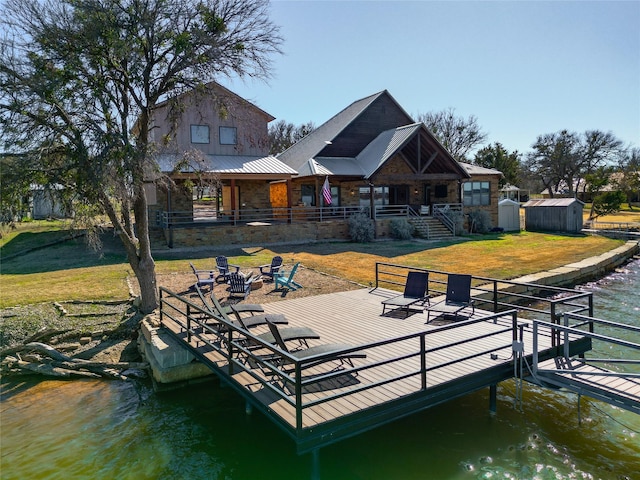 dock area with a water view, a yard, and a fire pit