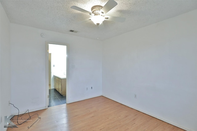 empty room featuring ceiling fan, light hardwood / wood-style flooring, and a textured ceiling