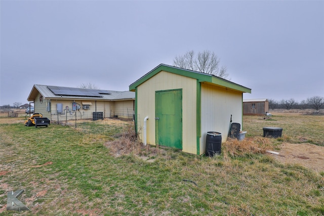 view of outbuilding featuring a yard, central AC unit, and solar panels