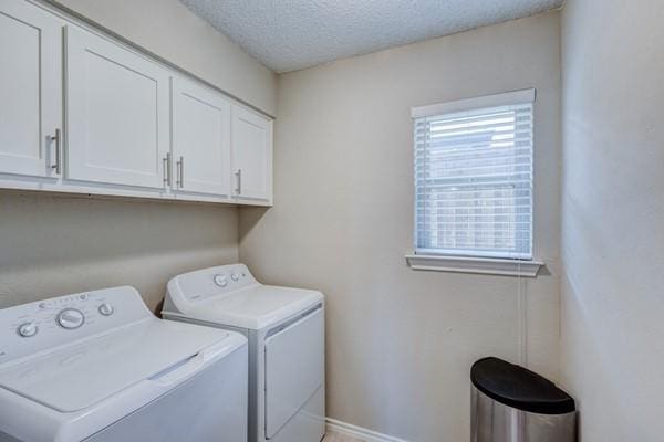 laundry room featuring cabinets, washing machine and dryer, and a textured ceiling