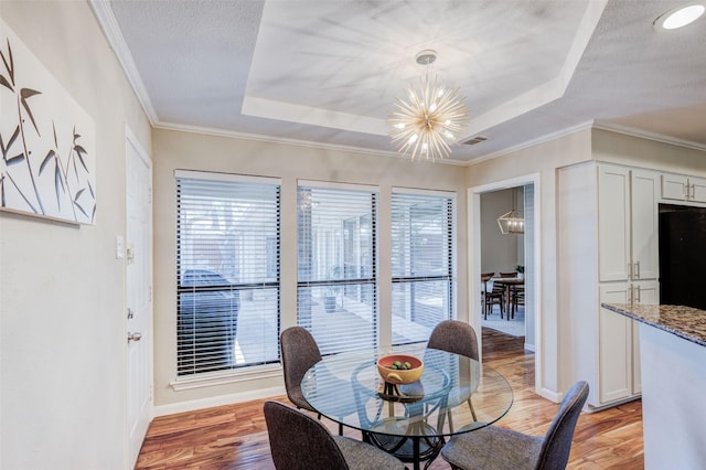 dining room with an inviting chandelier, a tray ceiling, a wealth of natural light, and light hardwood / wood-style floors