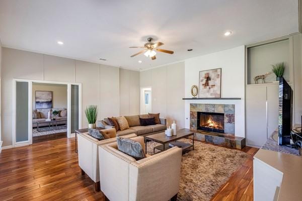 living room featuring a tile fireplace, dark hardwood / wood-style floors, and ceiling fan