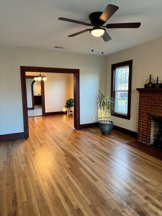 unfurnished living room featuring a brick fireplace, ceiling fan, and light hardwood / wood-style flooring