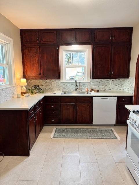 kitchen with sink, white appliances, light tile patterned floors, and backsplash