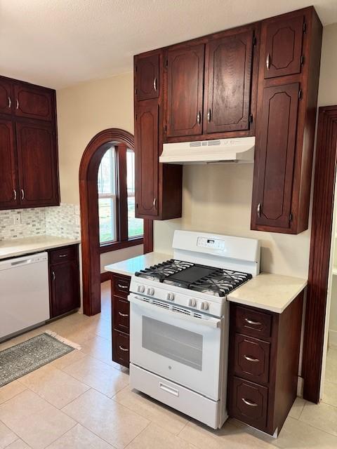 kitchen with backsplash, white appliances, and light tile patterned floors