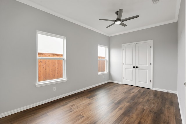 unfurnished bedroom with crown molding, ceiling fan, dark hardwood / wood-style flooring, and a closet