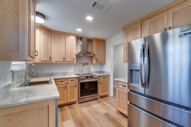 kitchen with wall chimney exhaust hood, sink, light brown cabinets, stainless steel appliances, and light hardwood / wood-style floors