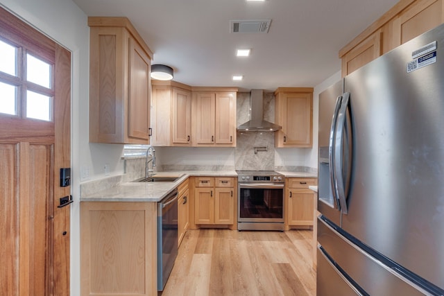 kitchen with wall chimney range hood, sink, stainless steel appliances, light hardwood / wood-style floors, and light brown cabinets