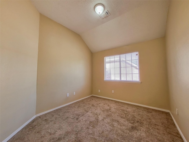 carpeted spare room with vaulted ceiling and a textured ceiling