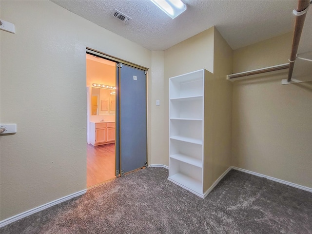 spacious closet with dark colored carpet