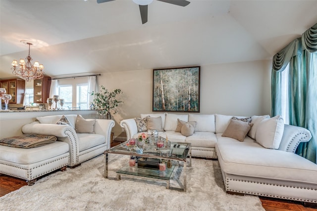 living room with ceiling fan with notable chandelier, vaulted ceiling, and hardwood / wood-style flooring