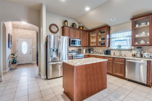 kitchen featuring sink, light tile patterned floors, stainless steel appliances, and a center island