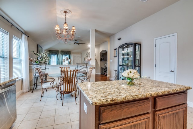 kitchen with hanging light fixtures, light stone countertops, stainless steel dishwasher, and light tile patterned floors