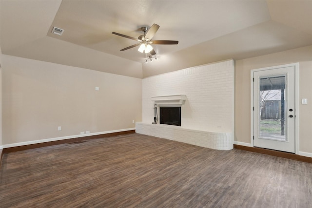 unfurnished living room with lofted ceiling, dark hardwood / wood-style floors, a tray ceiling, ceiling fan, and a fireplace