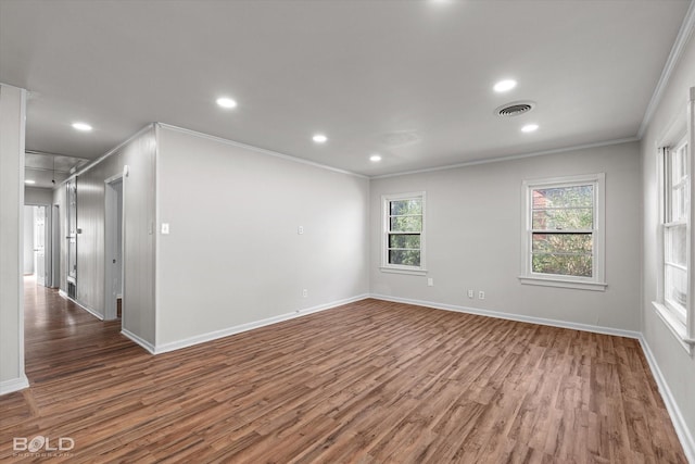 spare room featuring visible vents, attic access, ornamental molding, dark wood-type flooring, and baseboards