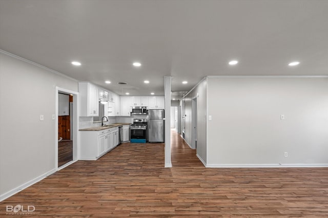 kitchen with recessed lighting, stainless steel appliances, a sink, white cabinetry, and dark wood finished floors