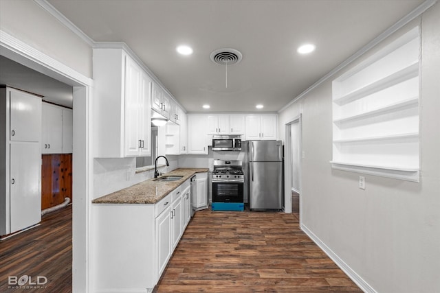 kitchen featuring visible vents, appliances with stainless steel finishes, white cabinets, a sink, and dark stone countertops