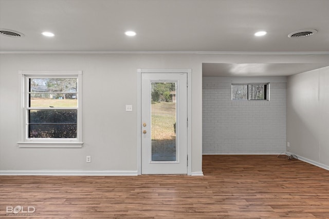 entryway featuring a wealth of natural light, ornamental molding, wood finished floors, and visible vents