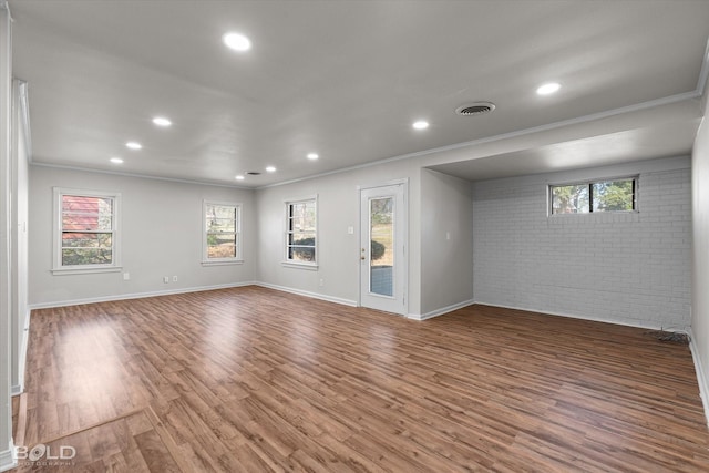 empty room with dark wood-style floors, brick wall, visible vents, and crown molding