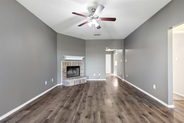 unfurnished living room featuring dark hardwood / wood-style flooring, a textured ceiling, a fireplace, and ceiling fan