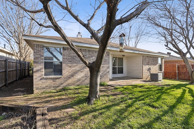 rear view of property with cooling unit, a lawn, and a patio