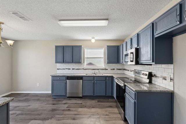 kitchen with blue cabinetry, appliances with stainless steel finishes, dark hardwood / wood-style flooring, and sink