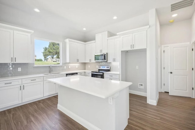 kitchen with sink, stainless steel appliances, a center island, and white cabinets