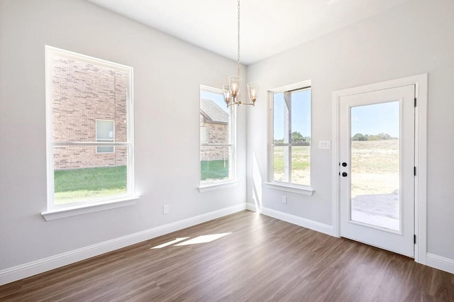 unfurnished dining area featuring dark hardwood / wood-style floors and a chandelier