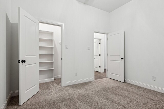 unfurnished bedroom featuring carpet flooring, a spacious closet, and a closet