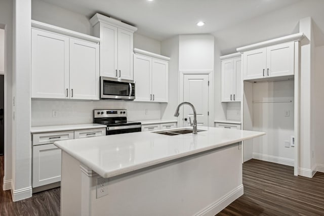 kitchen with appliances with stainless steel finishes, dark hardwood / wood-style floors, white cabinetry, sink, and a center island with sink