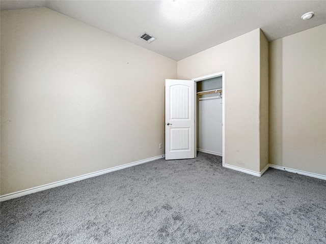 unfurnished bedroom with vaulted ceiling, carpet floors, and a closet